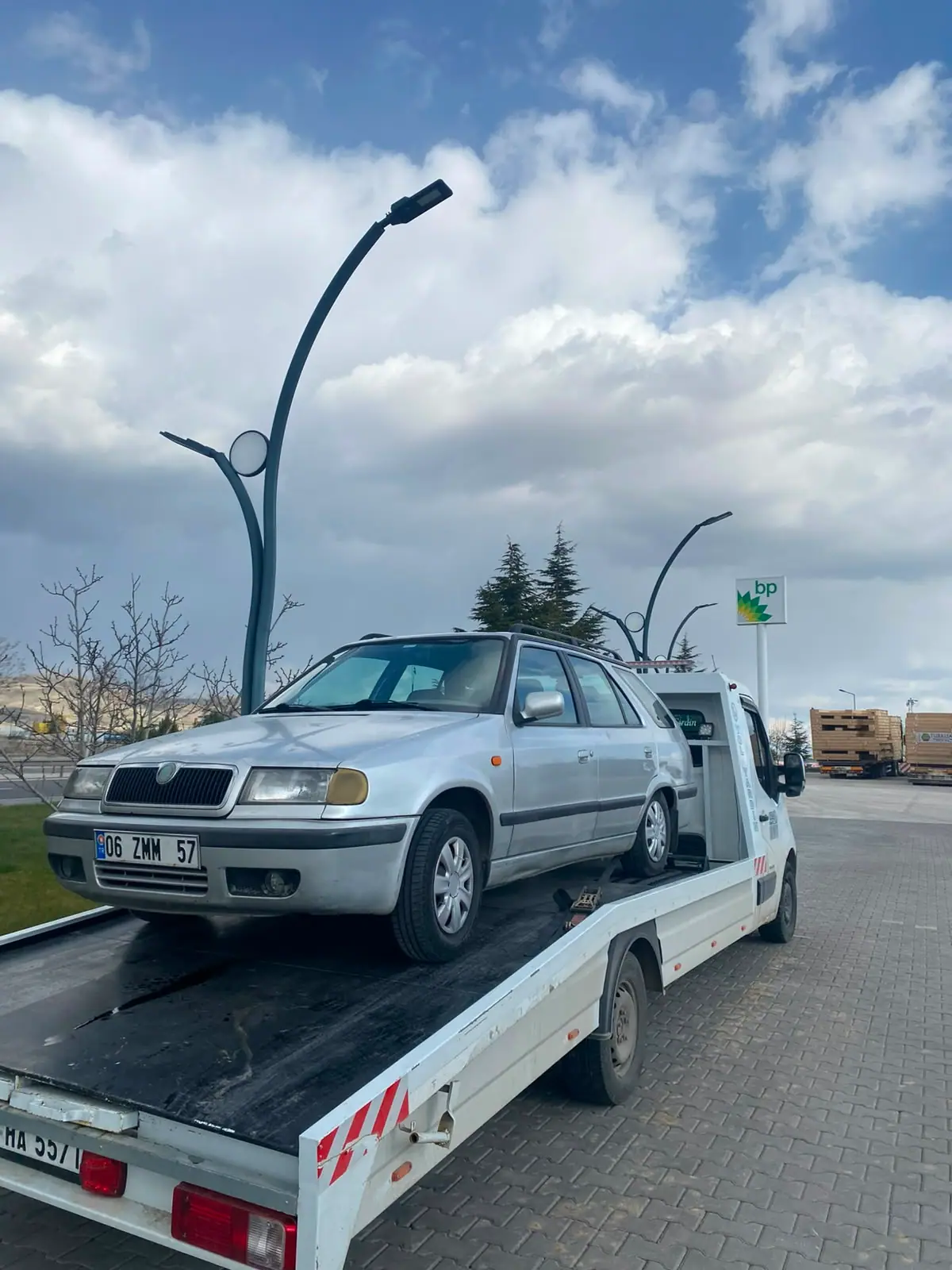 Akaryakıt istasyonu yakınında çekici platformunda taşınan gri station wagon otomobil